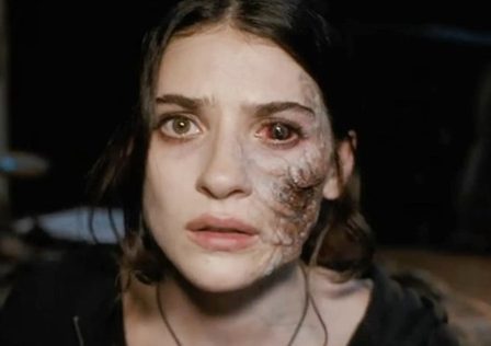 Screenshot-from-Until-Dawn-film-showing-a-female-character-with-a-bloodshot-eye-and-painful-looking-distortion-down-the-side-of-her-face.jpg