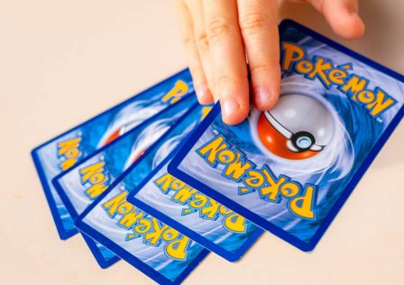 stock-five-pokemon-tcg-cards-face-down-on-a-table-with-a-hand-reaching-to-pick-one-up.jpg